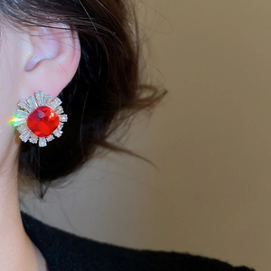 Close-up of vintage flower stud earring with red ruby-like stone worn by a model