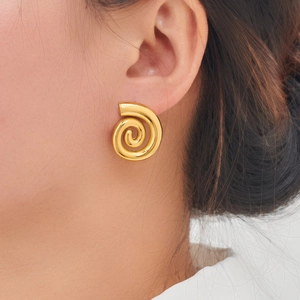 Gros plan de boucles d'oreilles spirales dorées sur un modèle, design géométrique poli