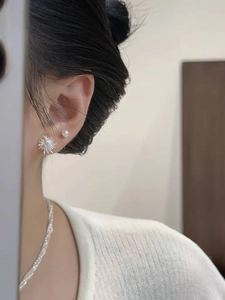 Detailed view of silver dandelion firework stud earrings and a delicate pearl necklace on model