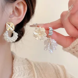 Set di orecchini eleganti con perle e fiori dorati abbinati a un maglione accogliente