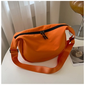 Close-up of vibrant orange nylon crescent bag on a white table with soft lighting