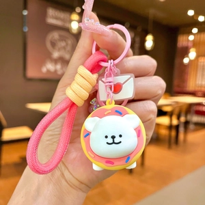 Close-up of white puppy keychain with doughnut headgear and pink braided wristlet strap