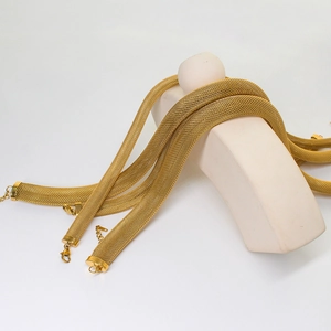 Detail view of a flat mesh woven gold necklace with a lobster clasp on a beige stand