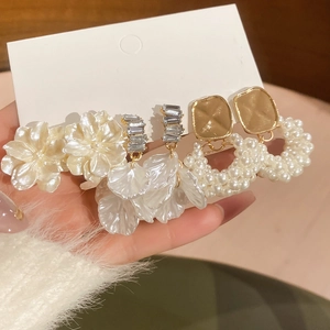 Dettaglio di orecchini a perla a fiore e petali con nappe su una carta da esposizione