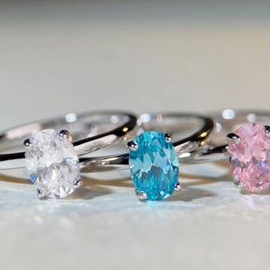 Macro shot of oval cut gemstones in blue, white, and pink with silver four-prong settings