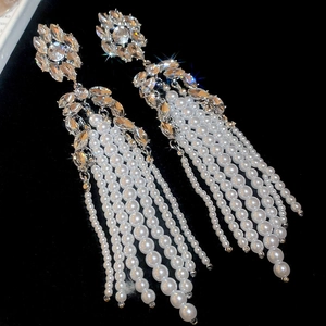 Macro detail of silver floral stud earrings with sparkling rhinestones and pearl tassels