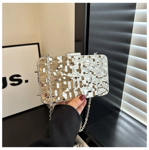 Detail of silver metallic evening bag with liquid-like wave texture and chain strap