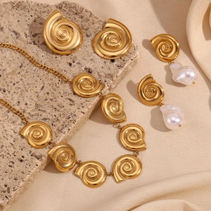Golden seashell jewelry set with white pearls on silk and stone background