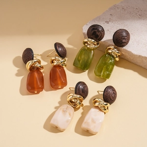 Detailed view of three pairs of vintage resin drop earrings in brown, green, and beige