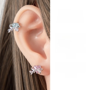 Detailed view of heart-shaped zircon earrings with silver bowknots on a model