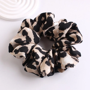 Close-up of leopard print scrunchie with soft silk texture and elegant folds on white