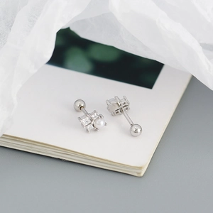 Detailed macro of S925 sterling silver pearl and zircon square stud earrings on book