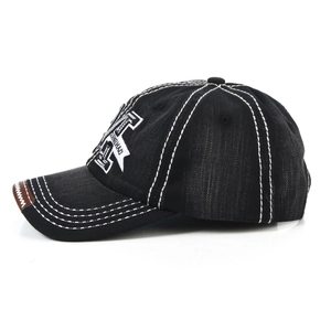 Close-up of vintage black denim baseball cap showing contrast stitching and M embroidery