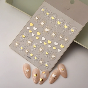 Close-up of gold 3D embossed heart nail stickers with elegant pearl texture and snowflake dots