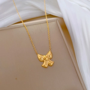 Minimalist gold titanium steel necklace with bow heart pendant on a beige tray
