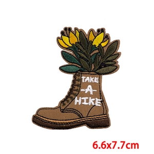 Detailed embroidery patch showing a hiking boot with yellow flowers and Take A Hike text
