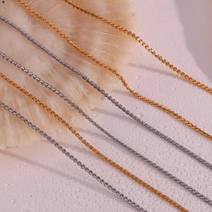 Detailed macro view of 18K gold and silver stainless steel snake chains on coral