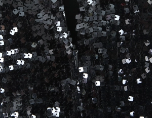 Détail du tissu à paillettes noires et fermeture éclair invisible sur une robe moulante