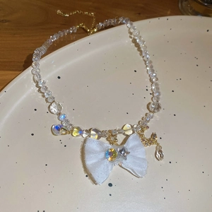 Close-up of pearl necklace with white fabric bow and golden celestial pendants on ceramic tray