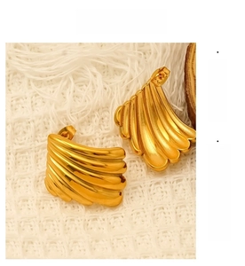 Détail des boucles d'oreilles dorées en forme d'éventail avec une texture nervurée