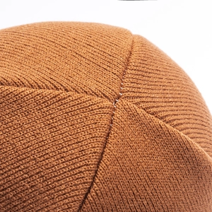 Detailed close-up of vertical ribbed knit texture and top stitching on caramel beanie