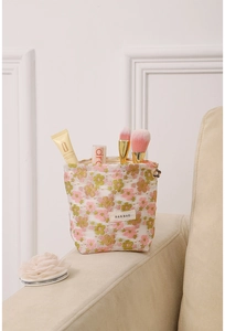 Detail of floral embroidery on white mesh makeup bag with zipper and logo label