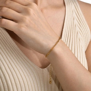 Detail of a gold-plated paperclip link bracelet on a woman's wrist with adjustable chain