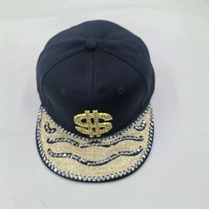Detail of hip hop snapback cap featuring a gold dollar sign and rhinestone wave brim