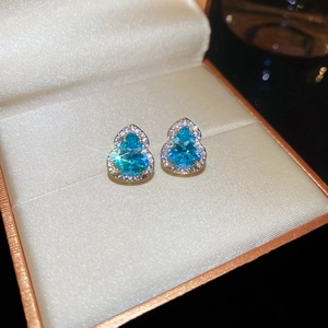 Vue macro détaillée des boucles d'oreilles gourde dorées avec zircons bleus éclatants