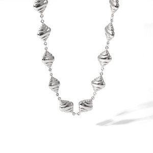 Macro shot of silver stainless steel spiral beads and shell textured necklace detail