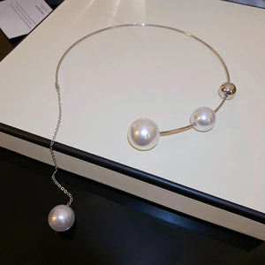 Detail of silver choker necklace featuring asymmetric white pearls on a display box