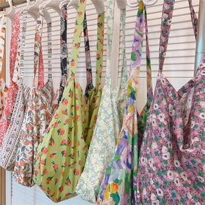 Sacs cabas en coton à fleurs suspendus en vert, violet et bleu sur des cintres blancs