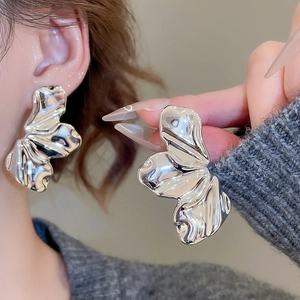 Macro shot of liquid metal style oversized silver heart earrings worn by a model