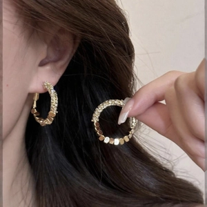Close-up of gold hoop earrings with pavé set crystals on a model's ear profile