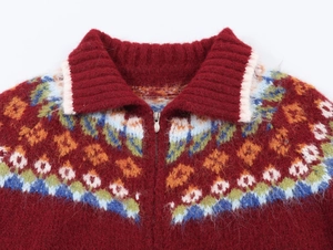 Close-up of bohemian jacquard pattern and silver zipper on red knit cardigan