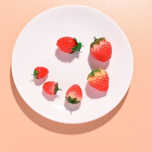 Detailed view of six red resin strawberry pendants in two sizes with metal loops