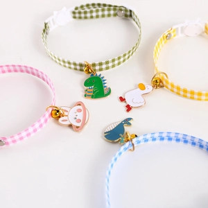Flat lay of four colorful plaid pet collars with cartoon metal pendants and safety buckles