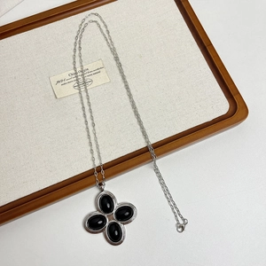 Macro shot of silver vintage cross pendant with black gemstones on a rustic wood tray