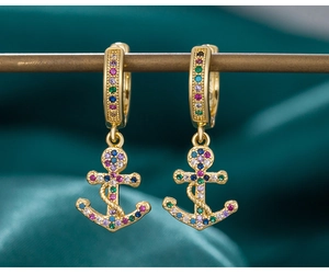 Close-up of gold anchor earrings with colorful crystals on dark green velvet