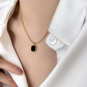 Close-up of minimalist gold chain necklace with black rectangular onyx pendant on model