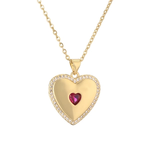 Golden heart pendant necklace with red gemstone and sparkling crystals on white background