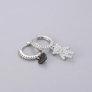 Detailed view of silver hoop earrings featuring pavé bear and magenta heart charms