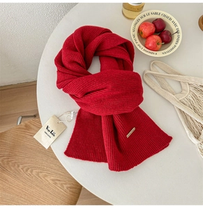 Detail of red 100% wool knit scarf featuring vertical ribbed pattern and metal logo tag