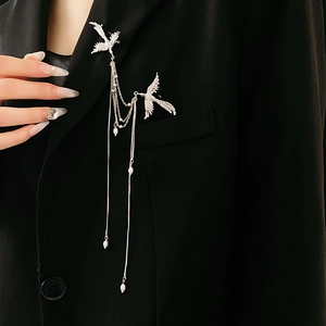 Detail of silver phoenix brooch with white pearl tassels on a black suit lapel