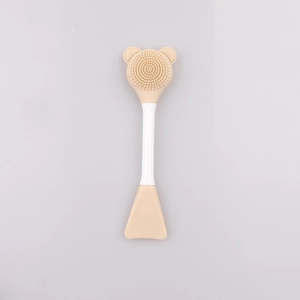 Detailed view of beige dual-sided silicone face brush with bear-shaped head and spatula