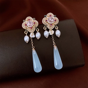 Detailed view of floral vintage earrings featuring pink stones and blue resin drops