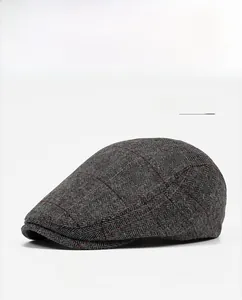 Detail showing the light gray herringbone tweed fabric and red plaid pattern on the flat cap