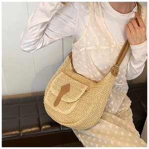 Detail of woven straw bag texture with brown faux leather flap and buckle strap