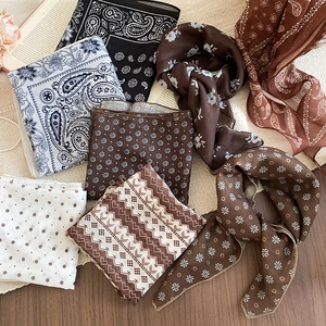 Flat lay of vintage floral and paisley silk neckerchiefs on textured woven mats