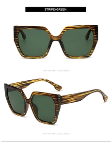 Detail view of square oversized sunglasses with striped frame and green lenses
